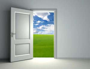 white open door inside empty room with view to green field and cloud sky background